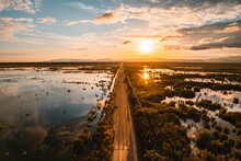 Bird's Eye View Of A Highway Surrounded By Wetlands In The Sunset