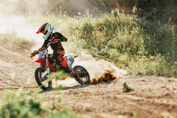 Live shot of junior sportsman, motorcyclist training on motorbike at hot summer day, outdoors. Motocross rider in action. Motocross sport, challenges