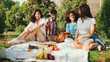 © Andrii Nekrasov - Happy smiling young multinational people at picnic on summer day outdoors. Friends have fun weekend together, relaxing in the park at picnic