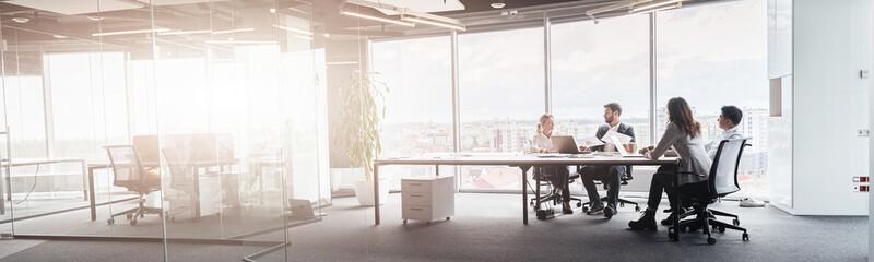 Creative business people working on project in modern office with panoramic view. Blurred background