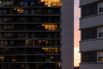 Sunset behind two buildings. Decorated light bulbs working on a balcony on the top floor. City life concept. High-quality photo