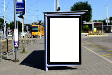 image composite of bus shelter at bus stop of blank light box and glass structure. green street setting. urban background. glass design. white poster ad commercial poster space. blurred background.