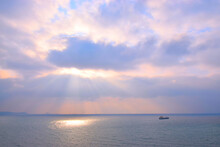 Dramatic Crepuscular Rays Or "God Rays" In Cloudscape With Boat On Open Sea