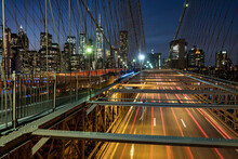 Traffic Crossing The Brooklyn Bridge With The Manhattan Skyline Beyond At Night, Manhattan, New York, United States Of America