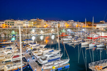 View Of Boats In Marina Overlooked By Whitewashed Buildings At Dusk, Ciutadella, Menorca, Balearic Islands, Spain