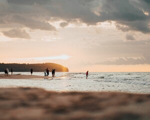 Scenic view of people on the beach at sunset in cloudy sky background