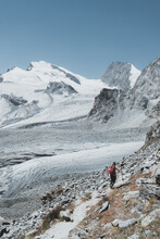 Vertical Image Of Hiker From Back Walking Towards Glaciers And Peaks