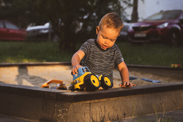 Wall Mural - Boy playing with toys in sandbox. Child having fun on playground in sandpit. Outdoor creative activities for kids. Summer and childhood concept