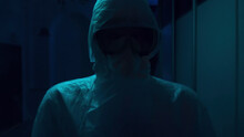 Horror Quest Details. Stock Footage. Close Up Of Unknown Person In Protective Suit And Mask, Frighteningly Standing In The Hall With Blinking Light.