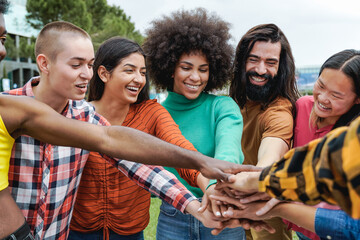 young group of people stacking hands together outdoor - diversity friends concept