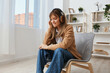 © SHOTPRIME STUDIO - Enjoyed free time young blonde student lady freelancer in warm sweater in headphones listen fav songs sitting in armchair at modern home interior. Music time Relaxing Cool playlist Concept. Copy space