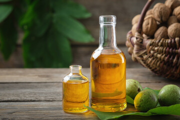 Wall Mural - Bottles of essential nut oil, green and ripe walnuts. Basket of nuts on background.