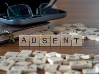 absent mot ou concept représenté par des carreaux de lettres en bois sur une table en bois avec des lunettes et un livre