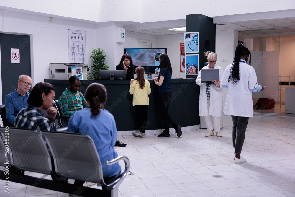 Front desk receptionist talking with young girl patient registering for ...