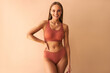 © Velista production - Attractive confident young woman posing on beige background in comfortable underwear and smiling.