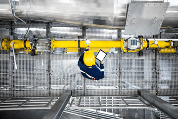 Top view of refinery worker checking gas pipeline installations and consumption in petrochemical factory.