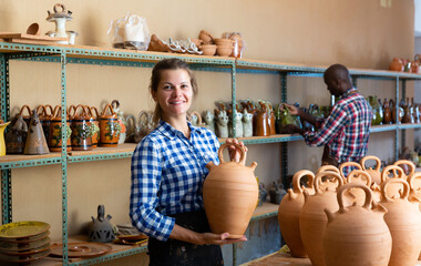 Wall Mural - Woman and man artisans in apron having ceramics in store warehouse. High quality photo