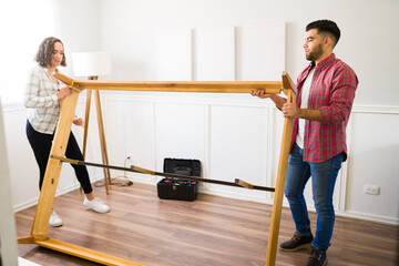 Wall Mural - Young woman and man assembling a bed frame for their bedroom