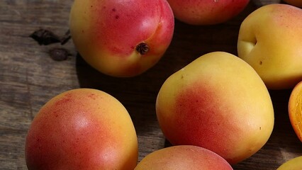 Wall Mural - Fresh ripe juicy yellow orange red apricot fruit pile whole cut half slice seed on rustic wood background flat lay top view pan move shift