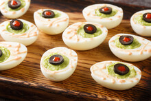 Funny Halloween Food Eyeballs Deviled Eggs Stuffed With Avocado Cream On A Wooden Tray On The Table. Horizontal