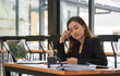 © Songsak C - Thoughtful Asian businesswoman in tension and looking for problem solution sitting at workplace desk while working on a laptop in an office.