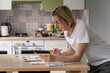 Mature woman looks at communal payments bills placed on table. Thoughtful single female of middle age looks unsatisfied with utility bill sums. Blonde lady examines papers in kitchen closeup