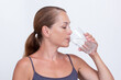 © Tatiana Foxy - Caucasian middle aged woman holding glass of pure water and drinking on white background