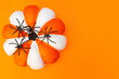 Halloween. White and orange striped pumpkin and black spiders. Place for text. Copy space. Flay lay. Top view. Layout for design. Orange background. Preparation for the Halloween holiday.
