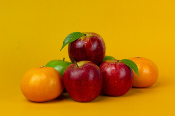 Wall Mural - Red apple and oranges isolated on yellow background with clipping path and full depth of field for cooking concept design