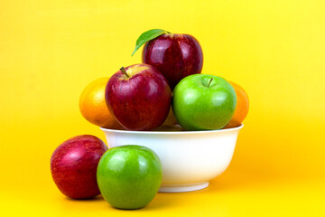 Poster - The concept of Healthy fruits, green apples, red apples, oranges isolated on yellow background. Creative composition of colorful of fruits isolated on yellow background