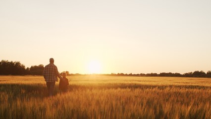 Farmer and his son in front of a sunset agricultural landscape. Man and a boy in a countryside field. Fatherhood, country life, farming and country lifestyle.