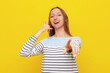 © Red Cristal - Young fair-haired woman wearing casual casual striped sweatshirt, smiling and doing talking on the telephone gesture and pointing to you. Indoor studio shot on yellow background