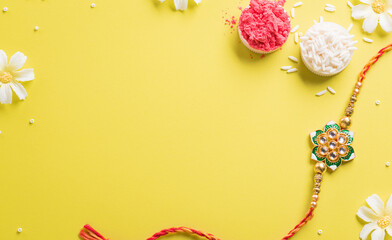 Raksha Bandhan, Indian festival with beautiful Rakhi and Rice Grains on yellow background. A traditional Indian wrist band which is a symbol of love between Sisters and Brothers