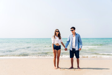 Wall Mural - Vacation romantic love young happy smile couple in honeymoon travel holiday trip standing on sand at blue sky sea beach having fun and relaxing together on tropical beach.Summer travel