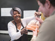 © Cultura Creative - Volunteer giving man vegetables in community food center