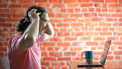 Profile of frustrated mature man on laptop computer seeing problem sad with anxiety.