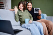 © Seventyfour - Portrait of smiling lesbian couple expecting baby and showing ultrasound image to family via video chat, copy space