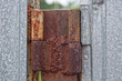 brown old rusty iron hinge on a gray metal door in the street