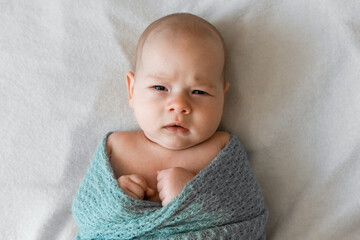 Wall Mural - Newborn baby looking surprised at the camera in white bed. Family, new life, childhood, beginning concept