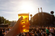 © 9parusnikov - Disposable beer glass in man's hand at a summer music festival.