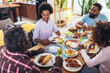 © Mediteraneo - A multi-generational African-American family enjoying food at their dinner table.