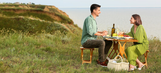 Wall Mural - Happy young couple having picnic in mountains