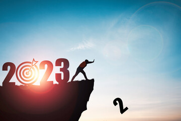 Wall Mural - Silhouette man push number two from clip with 2023 year and blue sky for preparation new business target when change new year concept.