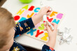 © Birute - Two year boy playing with wooden alphabet letters board. Letters wrapped in foil. Intellectual game, preschool implement for early education. Verbal and memory training exercise.