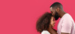 Leinwandbild Motiv Young African-American man kissing his girlfriend on red background with space for text