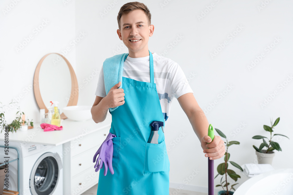 Smiling young man with mop in bathroom