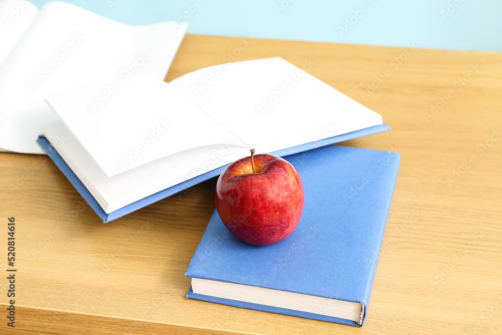 Red apple with school books on desk in classroom