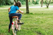 Girl Climbing On Bike In Park