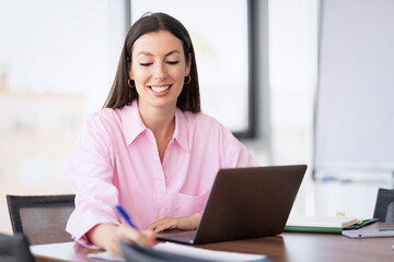 Wall Mural - Confident businesswoman using a laptop while sitting at the office