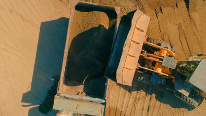 Poster - Excavator removing sand into dump truck. Scene. Top view of excavator loading sand into truck. Construction and grinding works with sand